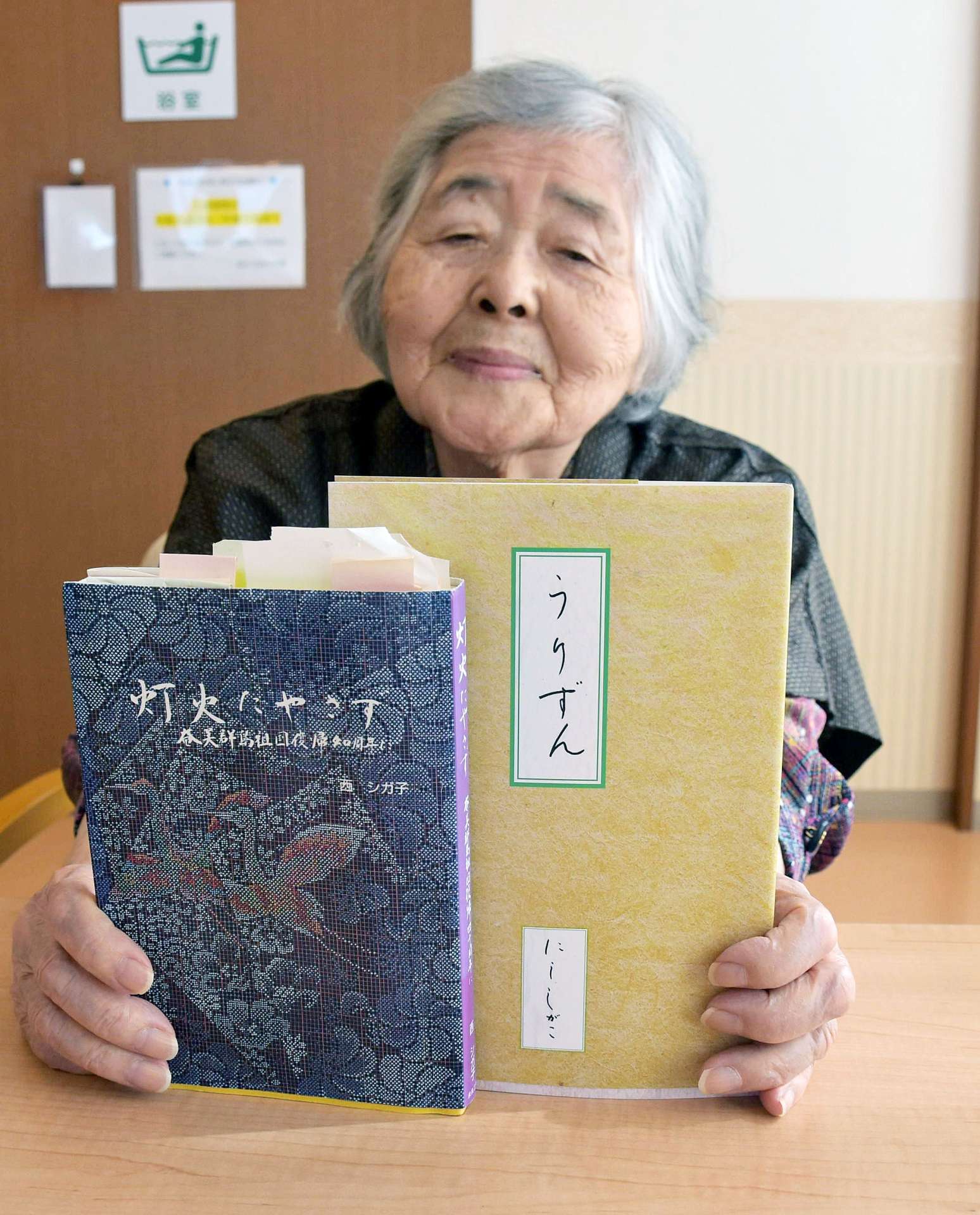 奄美群島の日本復帰運動について自身がつづった本を手にする西シガ子さん＝６日、奄美市
