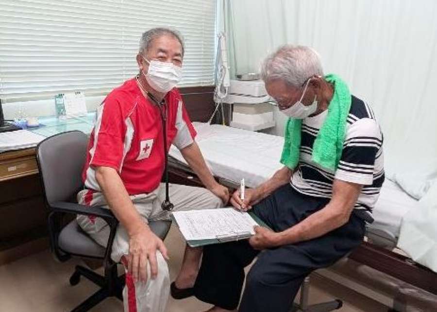 島民を診療する永井慎昌医師（左）＝６月２４日、十島村の悪石島診療所（鹿児島赤十字病院提供）