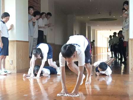 雑巾がけリレーで対戦する鹿児島女子高生と楠隼高生＝肝付町の楠隼中高一貫校