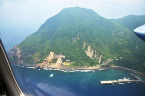 〈第10管区海上保安本部のプロペラ機から記者が撮影した悪石島の写真を見る〉やすら浜港付近。地震の影響か、山肌があらわになった斜面が見える＝９日午後１時５分