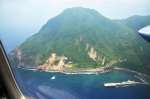 〈第10管区海上保安本部のプロペラ機から記者が撮影した悪石島の写真を見る〉やすら浜港付近。地震の影響か、山肌があらわになった斜面が見える＝９日午後１時５分