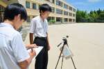 校庭の暑さ指数を計測する伊集院中学校生徒会保健部の生徒＝７日、日置市