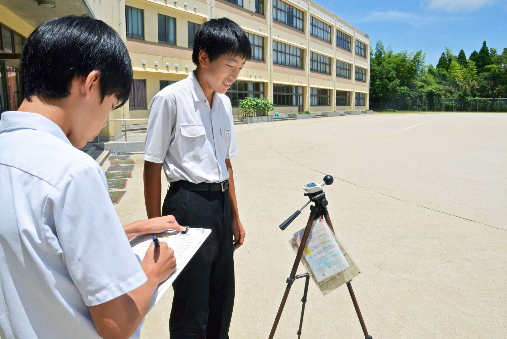 校庭の暑さ指数を計測する伊集院中学校生徒会保健部の生徒＝７日、日置市
