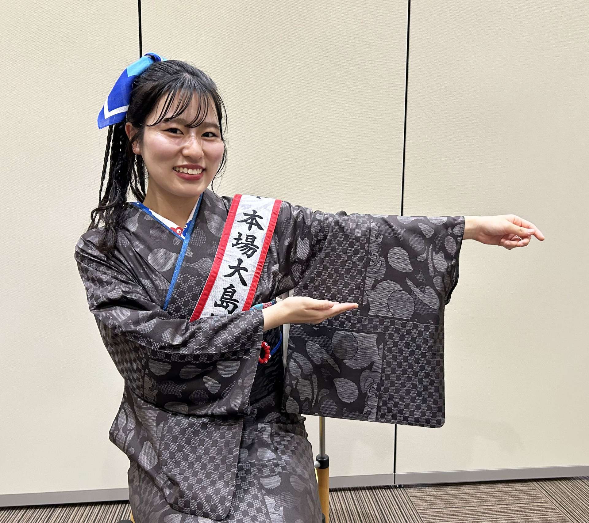 大島紬で表現した万博の公式デザイン「いのちの循環」を示す西原来海さん＝９日、南日本新聞社