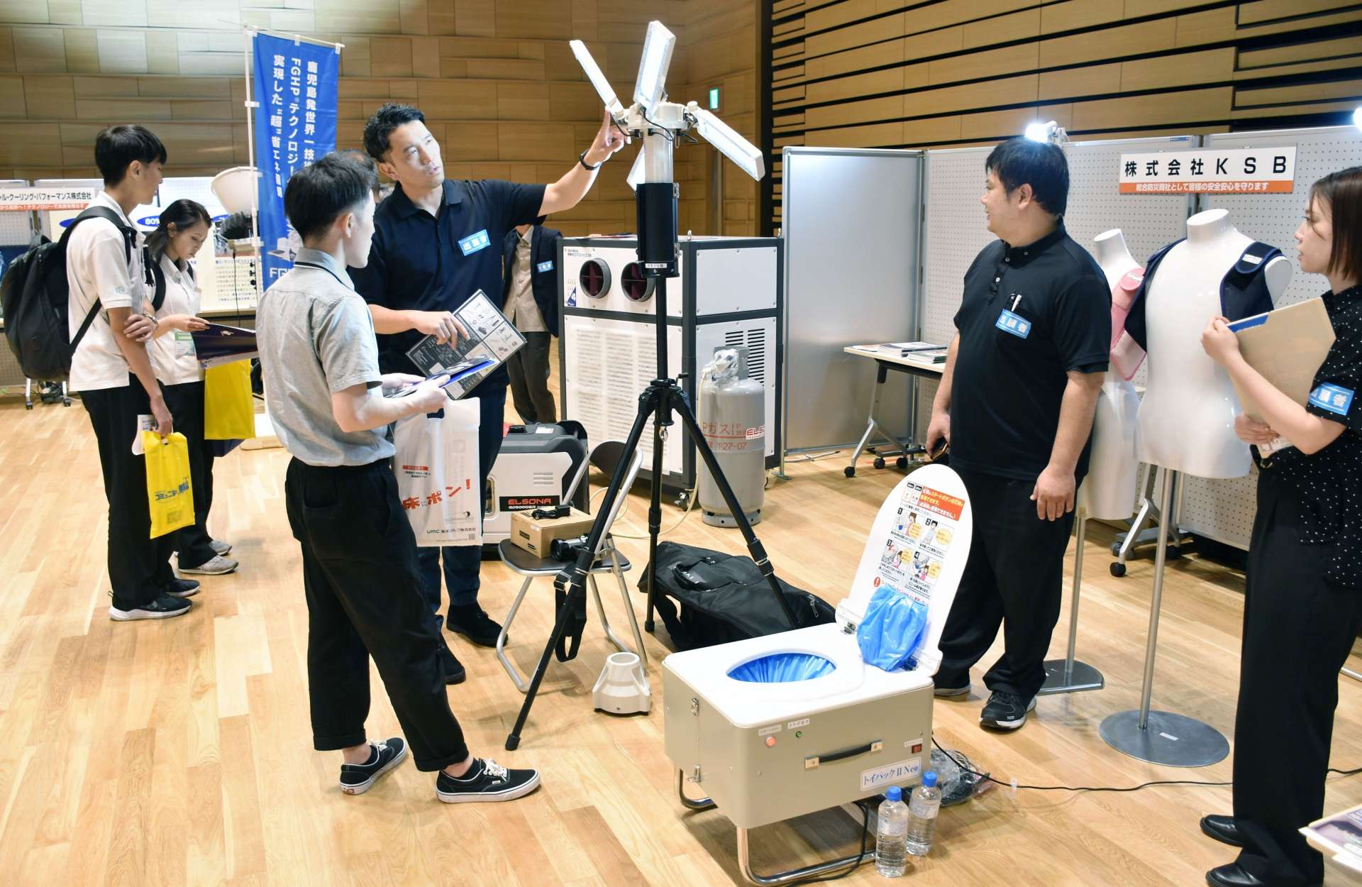 防災製品の説明を聞く来場者＝１６日、薩摩川内市のＳＳプラザせんだい