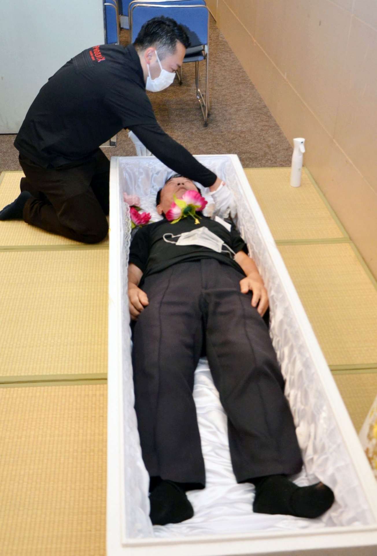 入棺体験をする男性（手前）＝１６日、鹿児島市のカクイックス交流センター