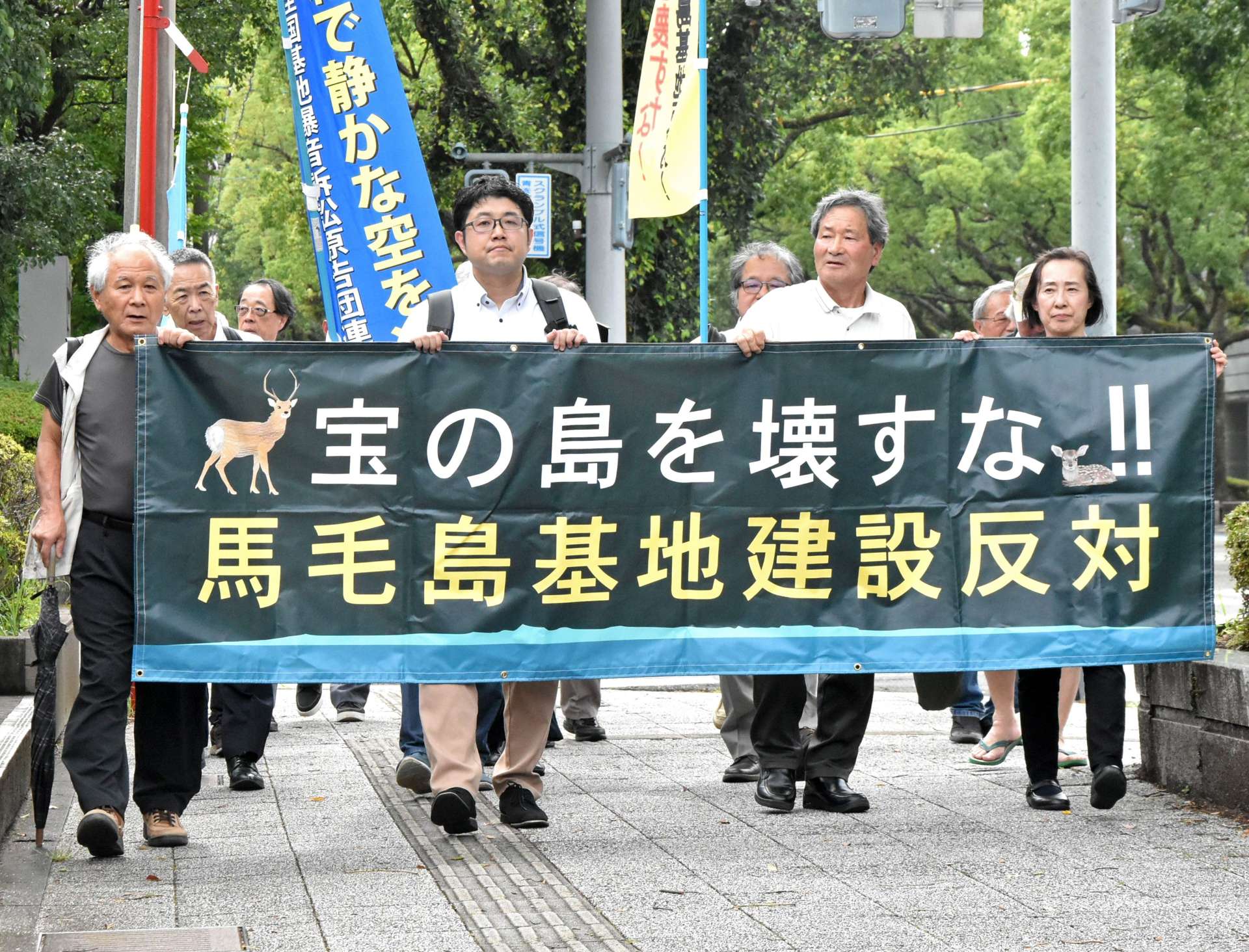 横断幕を持って裁判所に向かう原告ら＝１６日、宮崎市