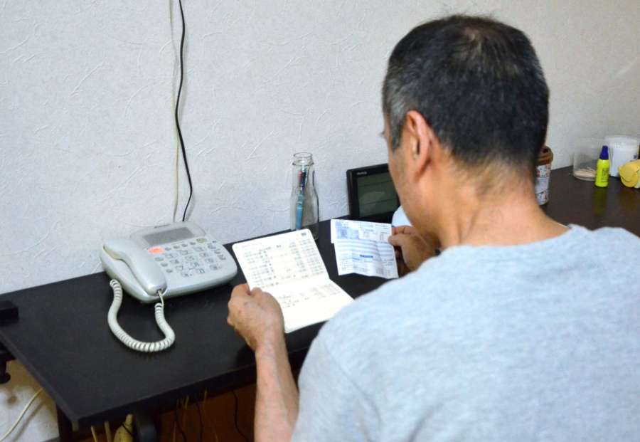 ガスの検針票と通帳残高を見る男性＝２日、薩摩川内市