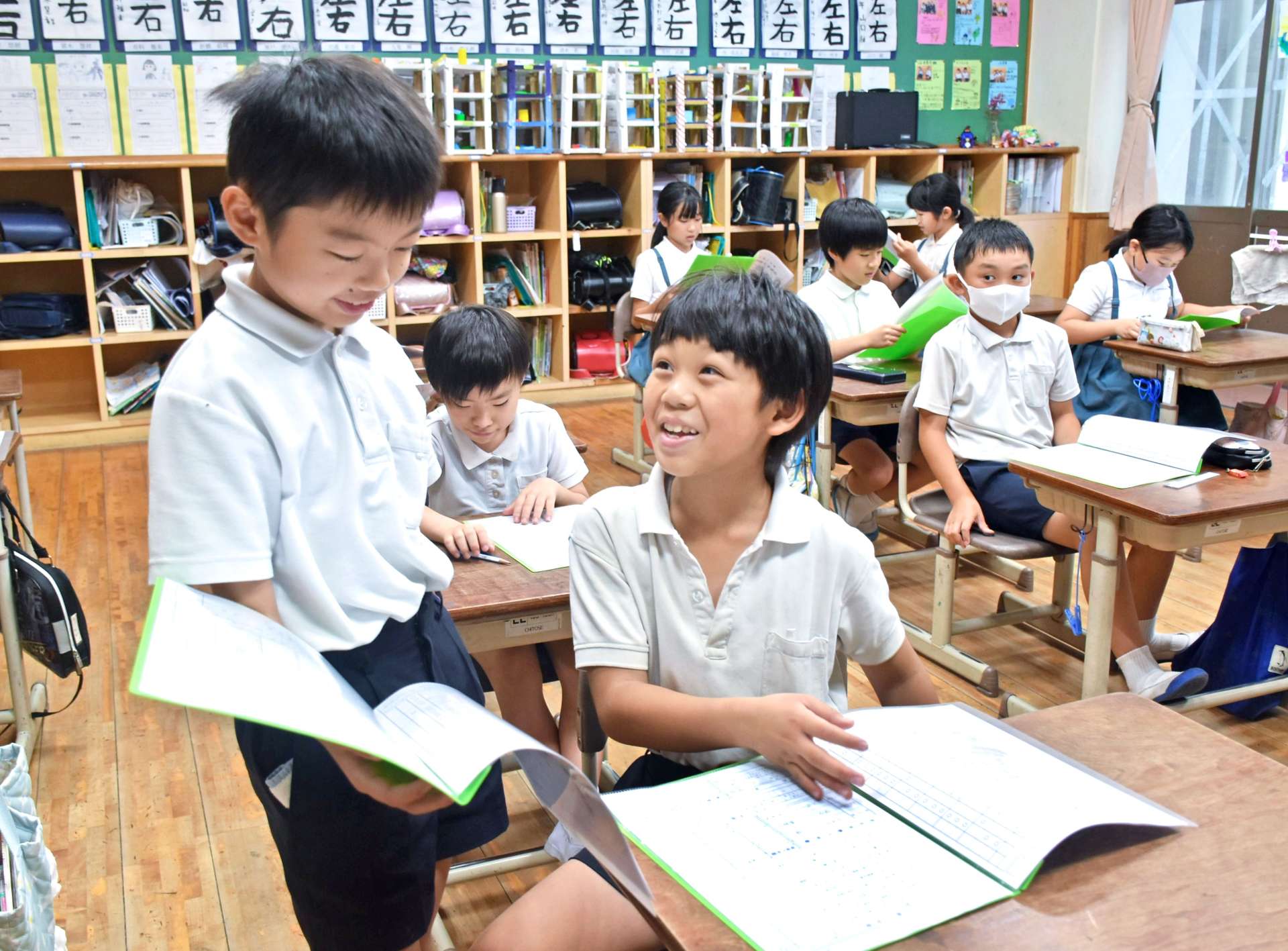 通知表を見せ合う児童たち＝１８日、霧島市牧園町高千穂の高千穂小学校