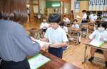担任教諭から通知表を受け取る児童＝１８日、霧島市牧園町高千穂の高千穂小学校