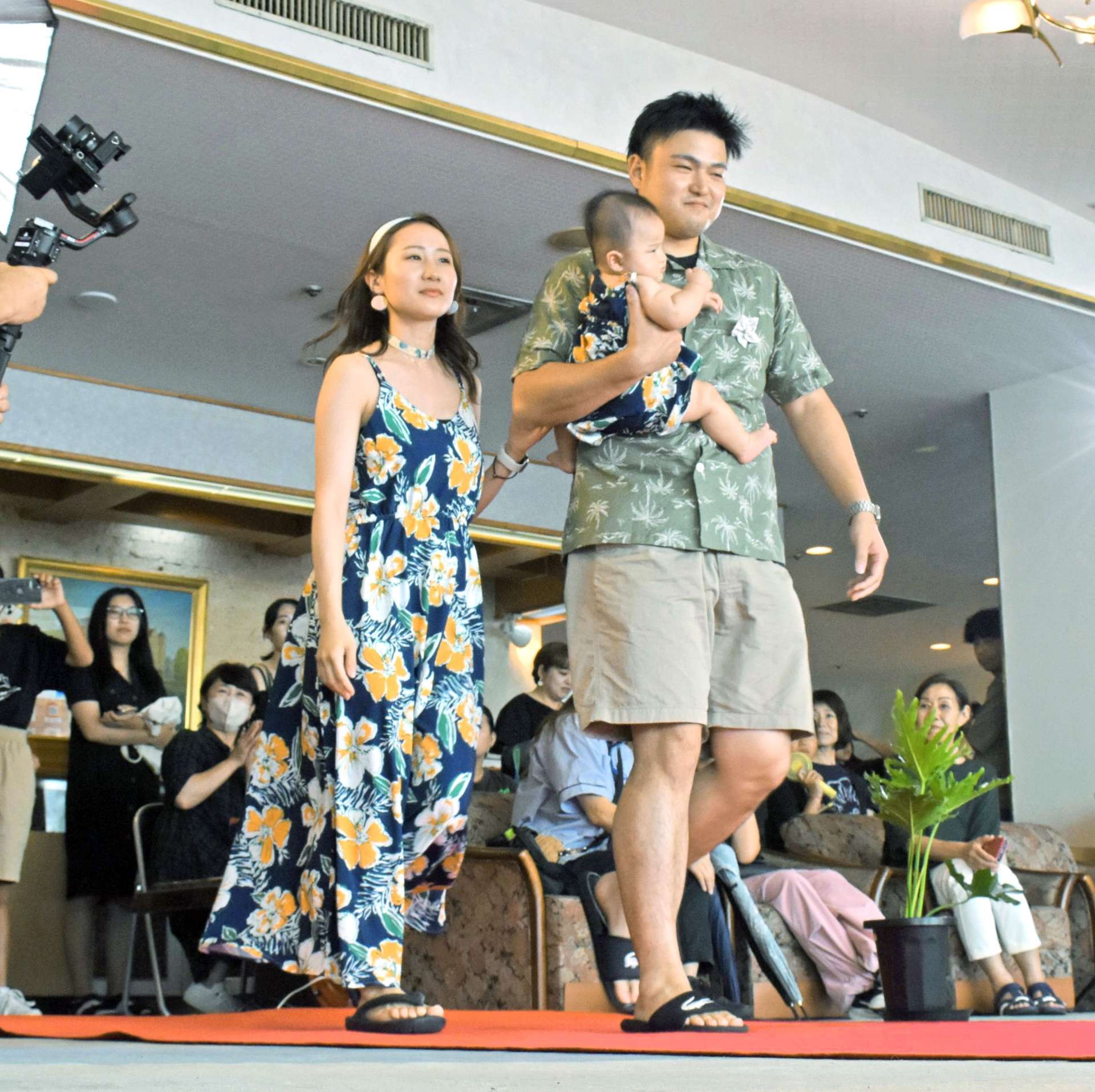 南国風のシャツやワンピース姿でランウェイを歩くモデル＝指宿市の指宿海上ホテル