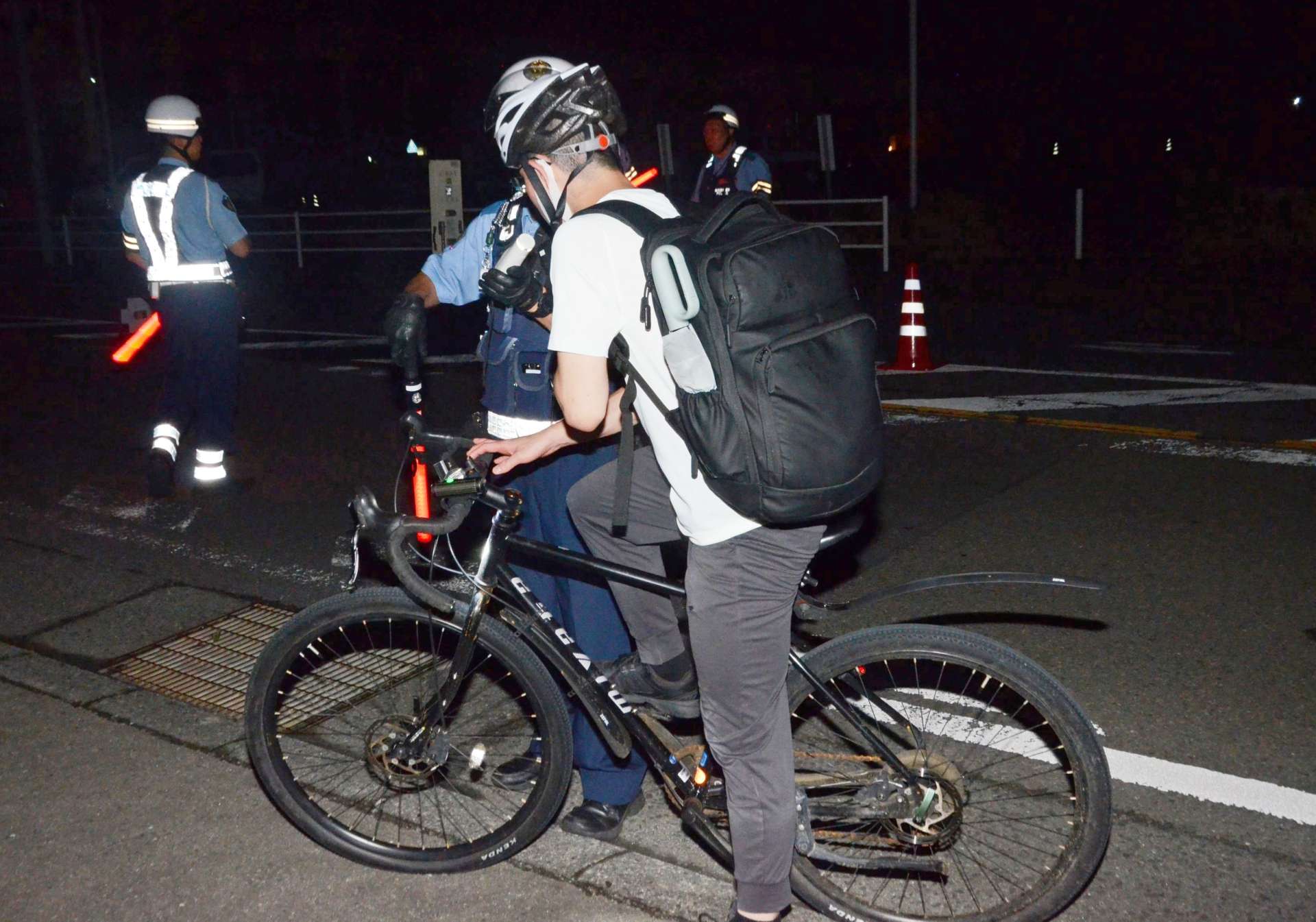 自転車を止め、呼気検査で運転手の飲酒の有無を調べる警察官＝１９日午前３時５５分ごろ、鹿児島市和田１丁目の国道２２５号（摘発とは関係ありません）