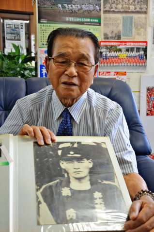 父・栄助さんの遺影を手に「苦しんでいる父に何もしてやれなかった」と振り返る神村勲さん＝いちき串木野市の神村学園