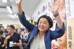 支持者らに大きく手を振り笑顔を見せる尾辻朋実さん＝２０日午後８時４３分、鹿児島市加治屋町