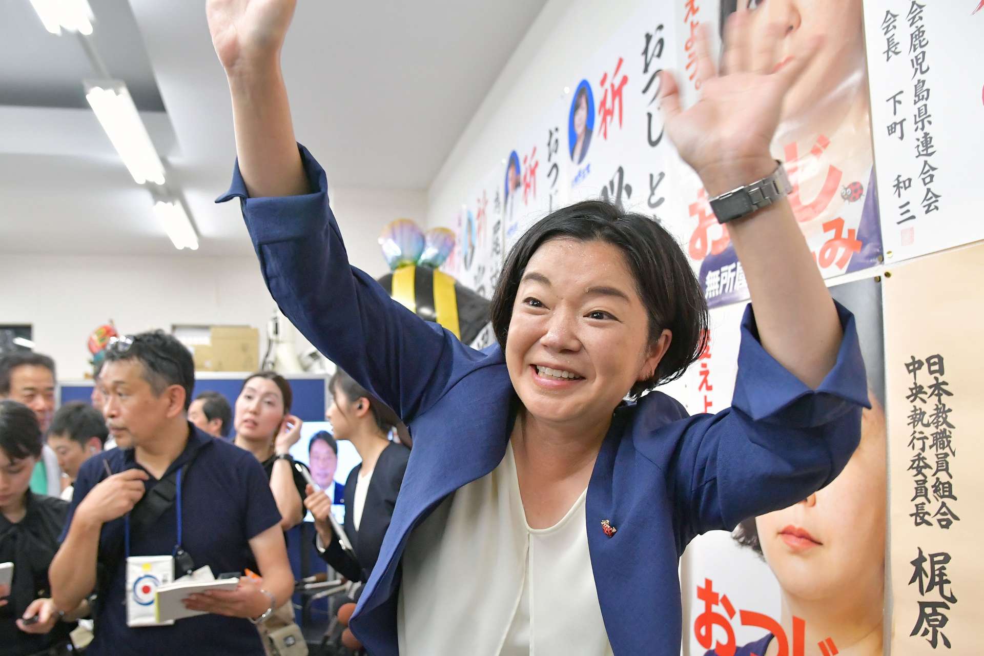 支持者らに大きく手を振り笑顔を見せる尾辻朋実さん＝２０日午後８時４３分、鹿児島市加治屋町