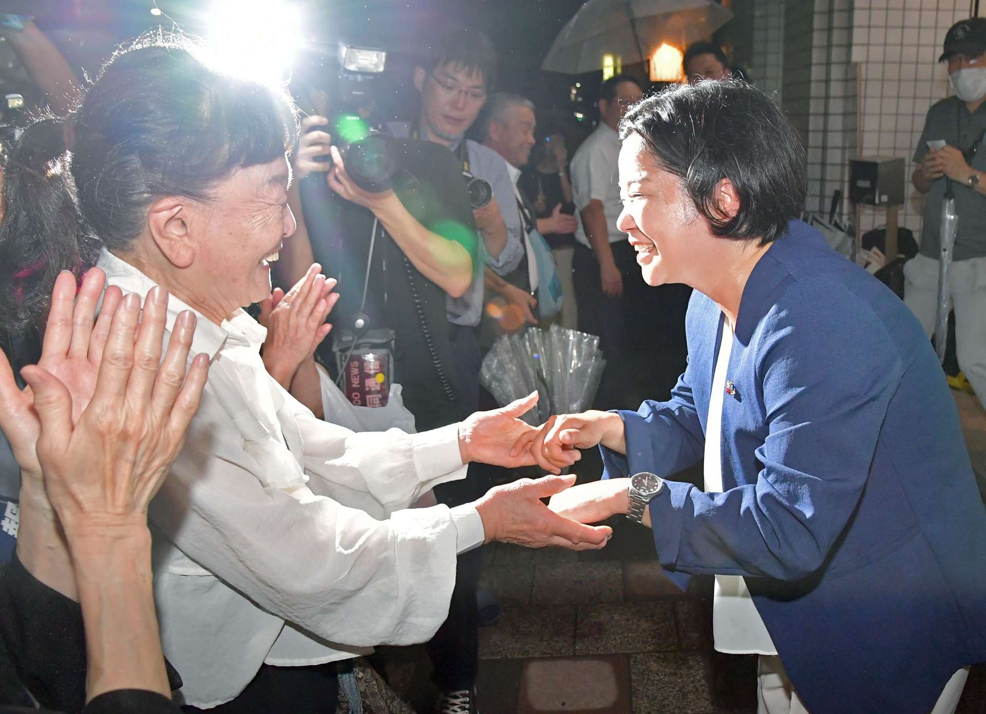 支持者と当選を喜び合う尾辻朋実さん（右）＝２０日午後８時５６分、鹿児島市加治屋町