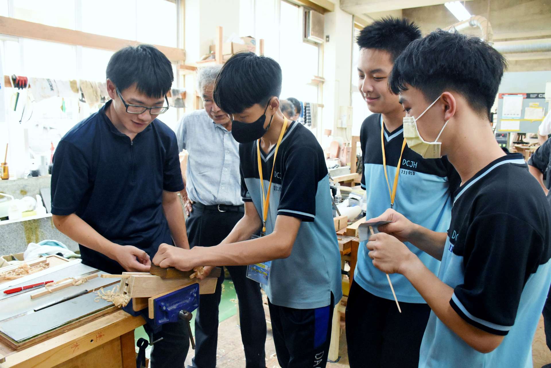 高校生（左）に教わりながら箸作りに挑戦する台湾の中学生＝１６日、出水市の出水工業高校
