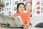事務所で自身の当選を報じる新聞記事を読む尾辻朋実さん＝鹿児島市加治屋町