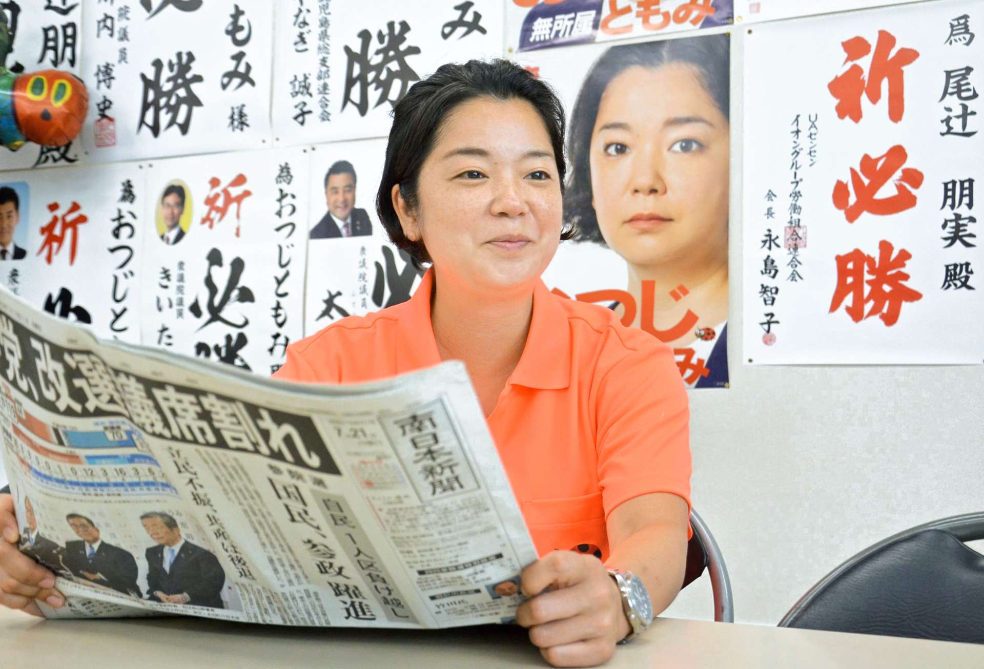 事務所で自身の当選を報じる新聞記事を読む尾辻朋実さん＝鹿児島市加治屋町