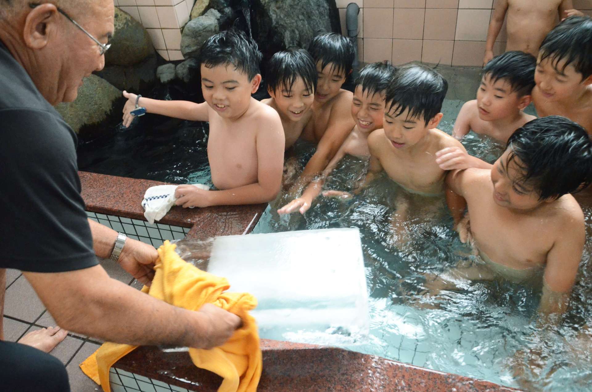 氷の投入に目を輝かせる子どもたち＝２２日午後３時半、鹿児島市下荒田３丁目の錦湯