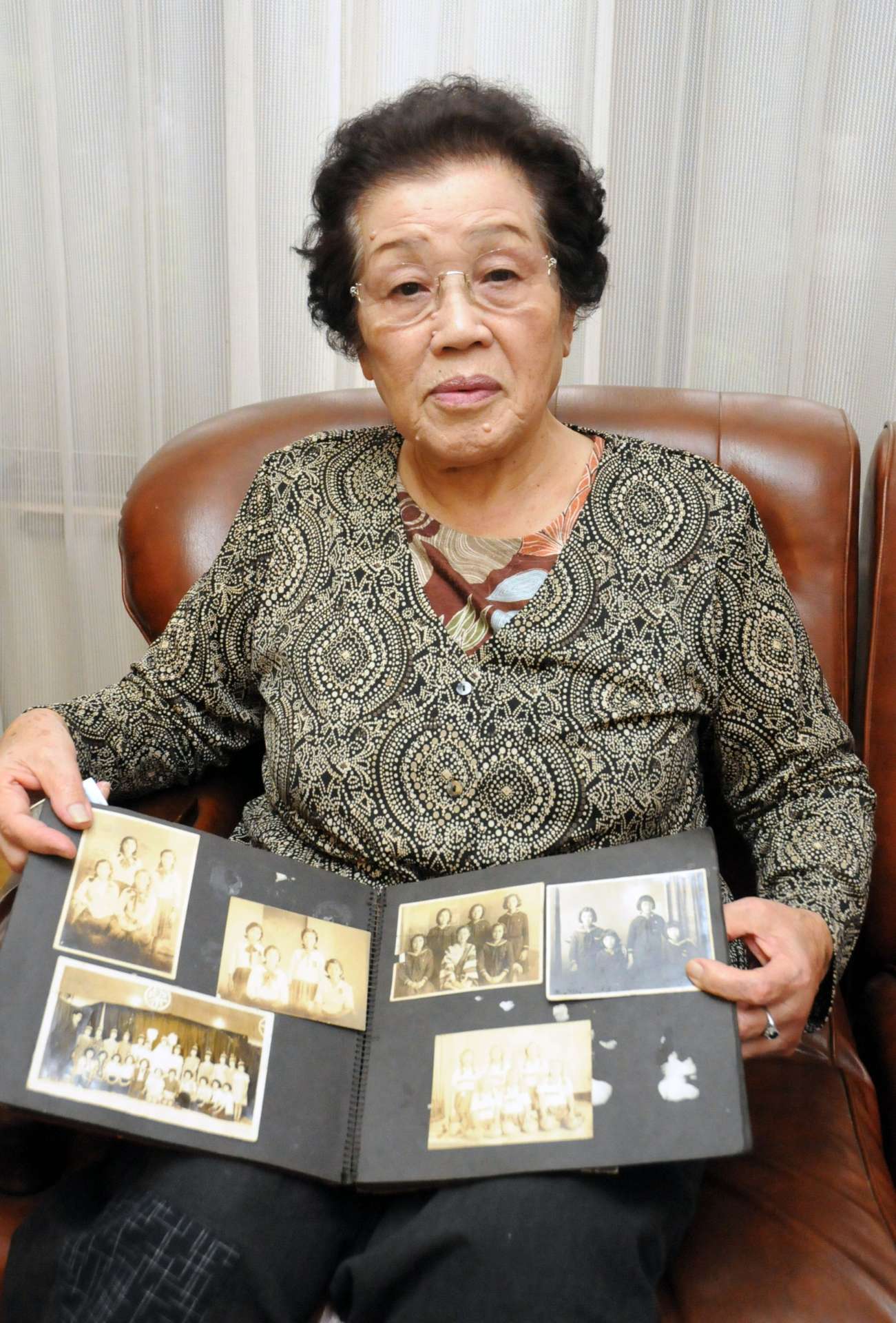 戦時中の写真を手に、当時を振り返る天野凉子さん＝志布志市志布志町安楽