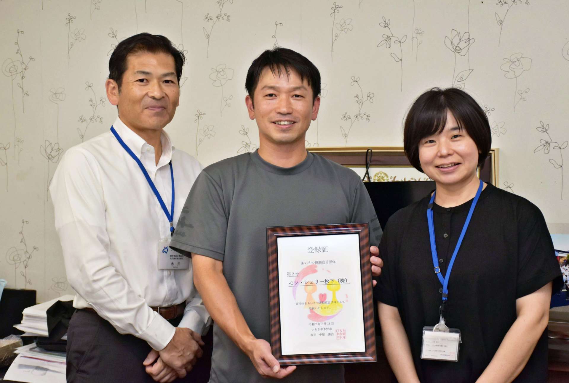 市から「あいさつ運動宣言団体」の登録証を受け取ったモン・シェリー松下の松下考太社長（中央）＝いちき串木野市のモン・シェリー松下