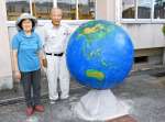手製の地球儀をきれいにした佐々木剛さん（右）と妻ミノエさん＝出水市の東出水小学校