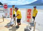 津波注意報の発表を受け、遊泳禁止の看板を設置する監視員ら＝３０日午前１０時４３分、鹿児島市吉野町の磯海水浴場
