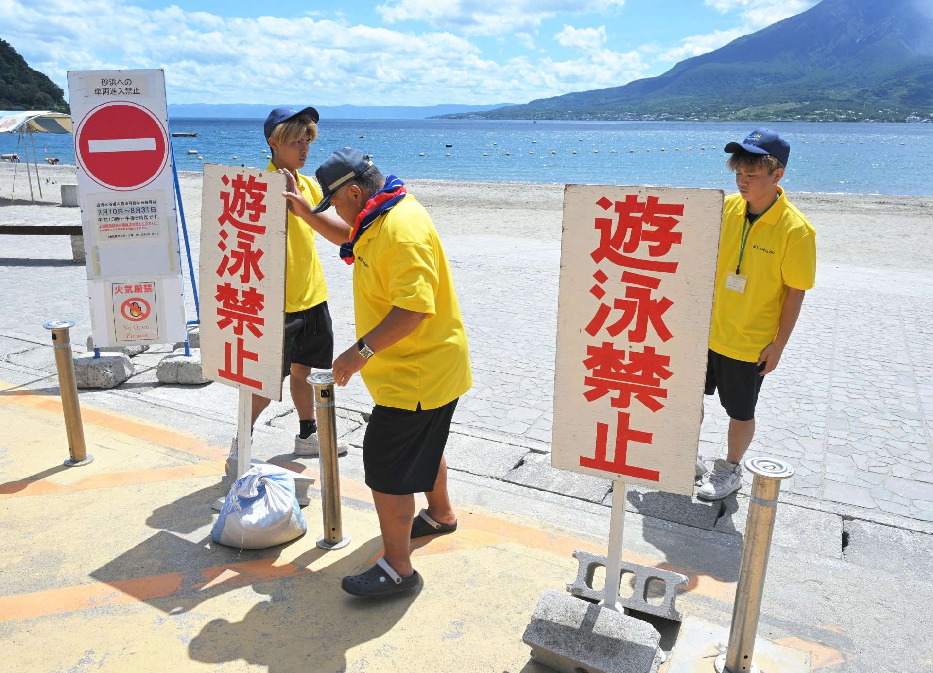 津波注意報の発表を受け、遊泳禁止の看板を設置する監視員ら＝３０日午前１０時４３分、鹿児島市吉野町の磯海水浴場