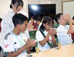 マダガスカルの学生に茶道を教えるえびの市おもてなしチームの小牧琴美さん（後列左）＝同市原田の飯野高校