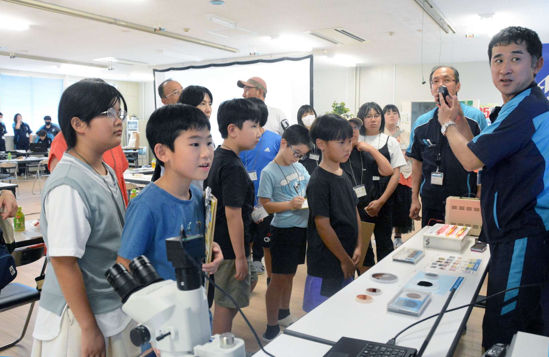 半導体についての説明に耳を傾ける小学生＝日置市のレゾナック・オプトエレクトロニクス鹿児島