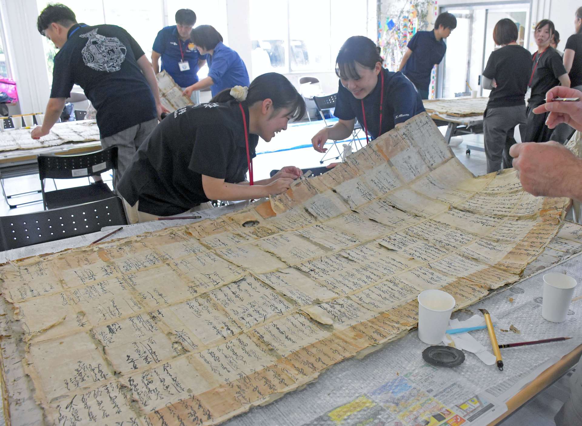 ふすまの下貼りから出てきた古文書を記録する参加者＝志布志市の志布志地区公民館分室