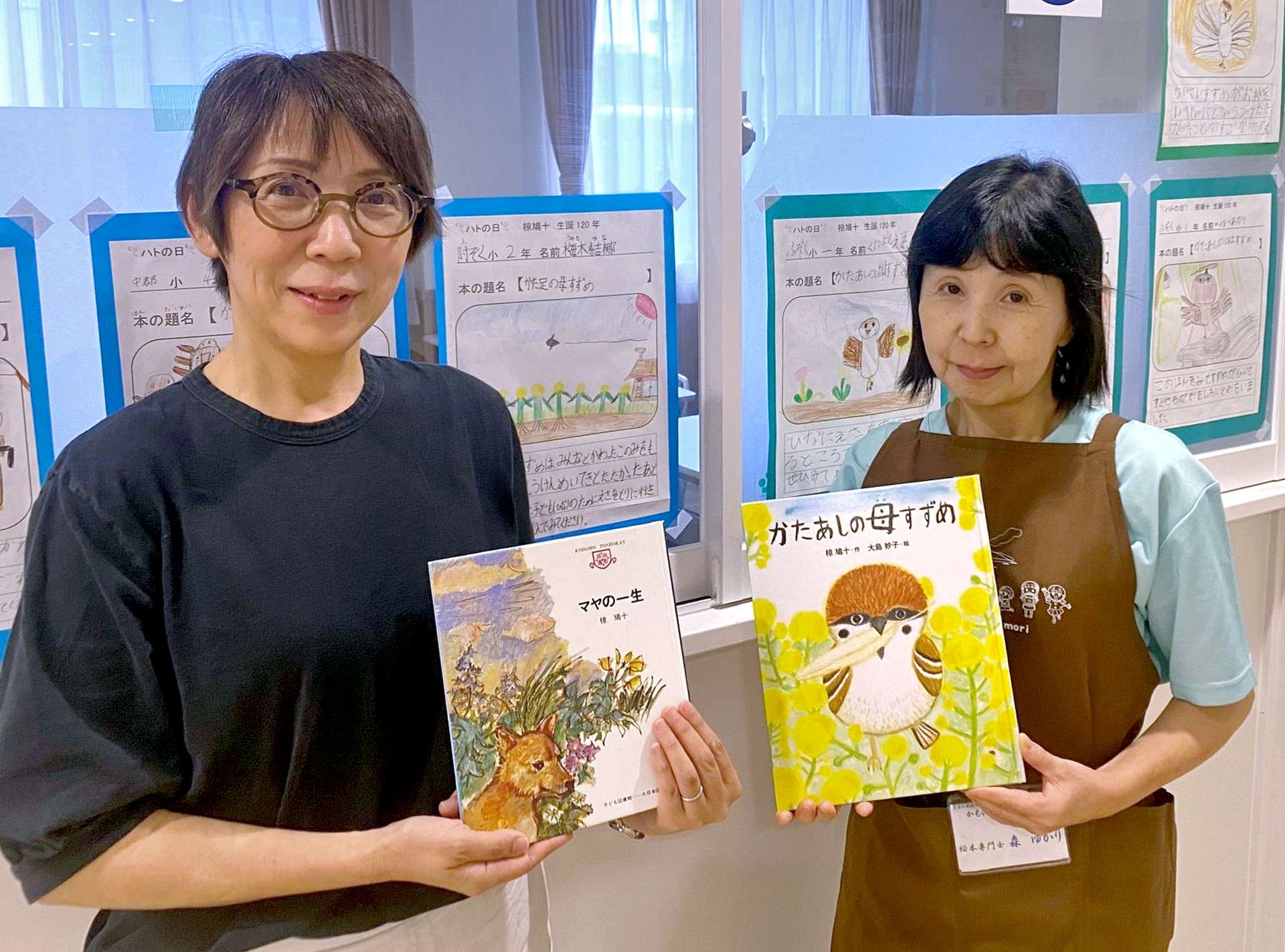 椋鳩十の本を手にする絵本専門士の久津輪美貴さん（左）と森ゆかりさん＝鹿児島市の「かもいけみらいの森」