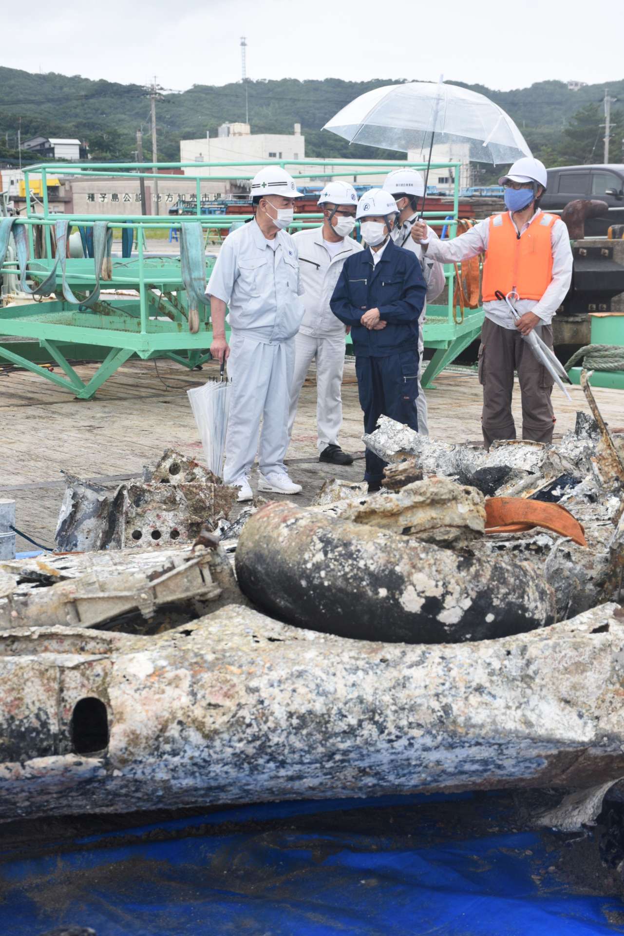 引き揚げられた機体を視察する尾辻秀久会長（中央）ら＝２０２１年６月、西之表市栄町