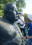 ブラシで西郷銅像の顔を洗う鹿児島第一ライオンズクラブのメンバー＝鹿児島市城山町