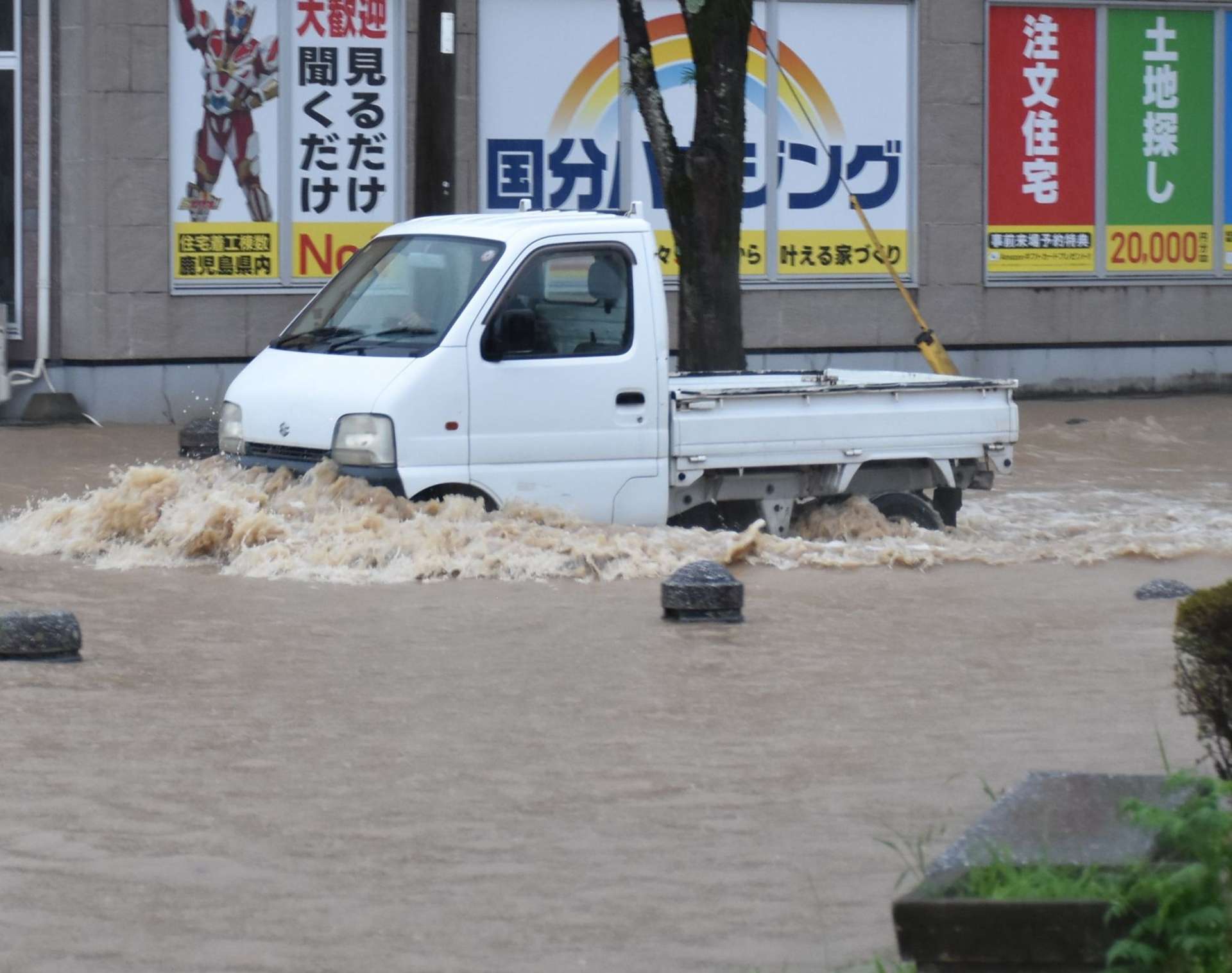冠水した道路を進む車＝８日午前６時５５分ごろ、霧島市国分中央３丁目