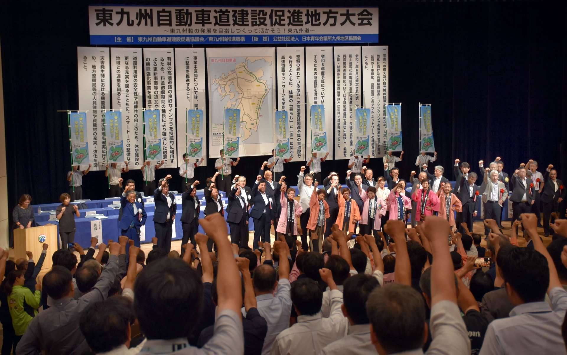 大会決議を採択し、がんばろう三唱をする参加者＝霧島市の国分ハウジングホール
