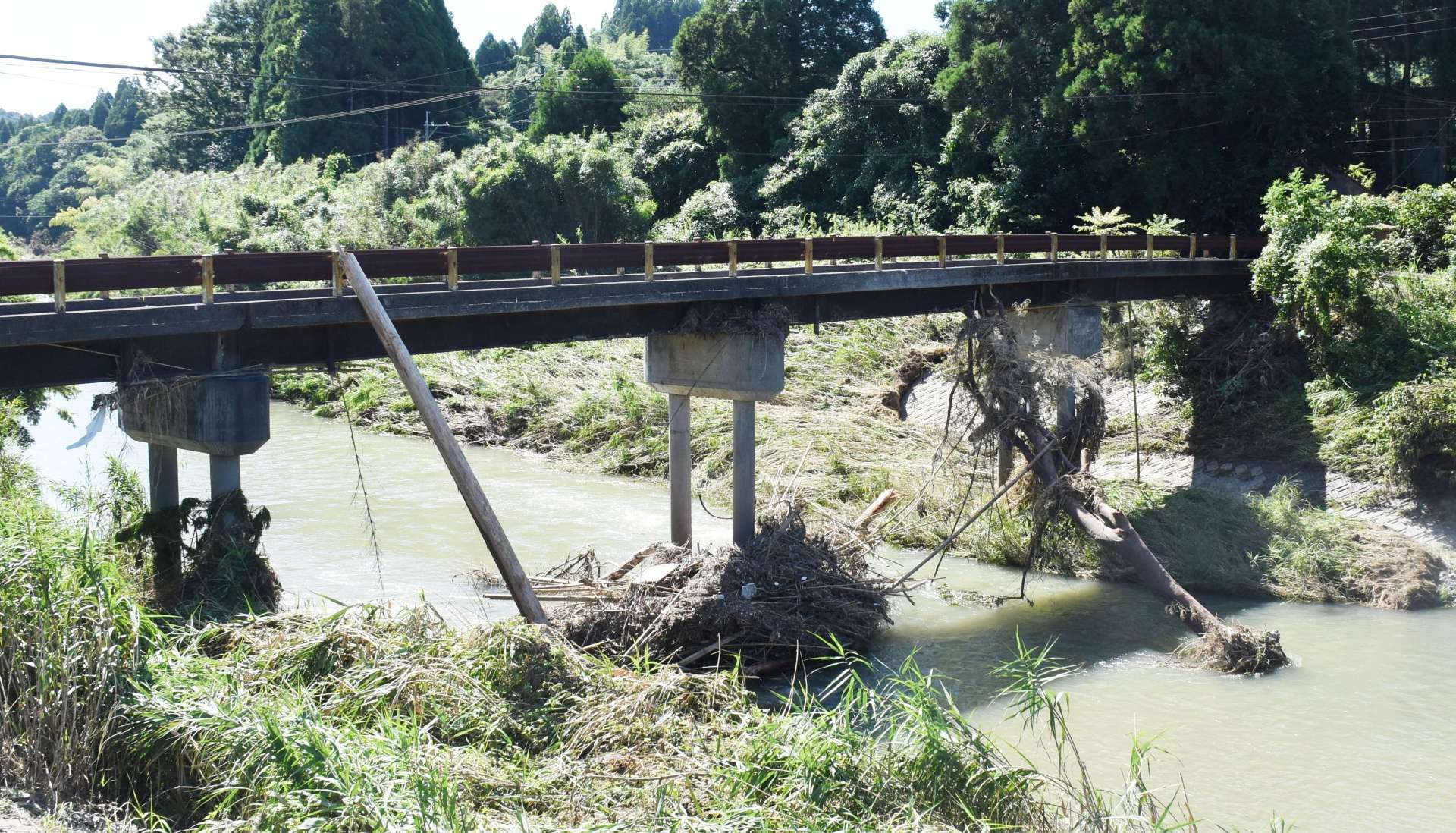 流木などがひっかかった状態の下川原橋。グループホームは対岸にある＝１３日、曽於市末吉町岩崎