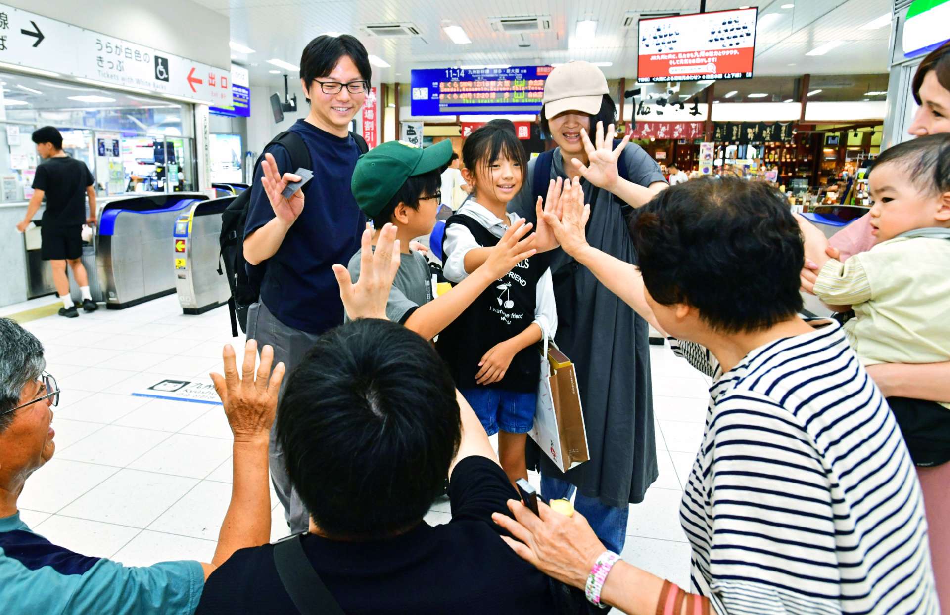 九州新幹線の改札口前で別れを惜しむＵターン客＝１６日午前、鹿児島市のＪＲ鹿児島中央駅