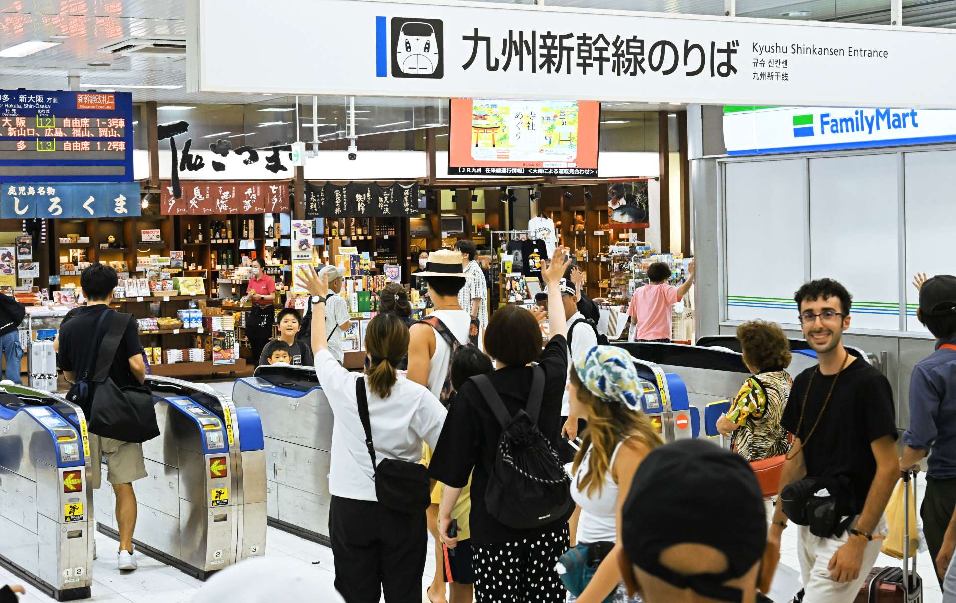 〈最後まで手を振り〉改札口前で別れを惜しむＵターン客＝１６日正午すぎ、鹿児島市のＪＲ鹿児島中央駅
