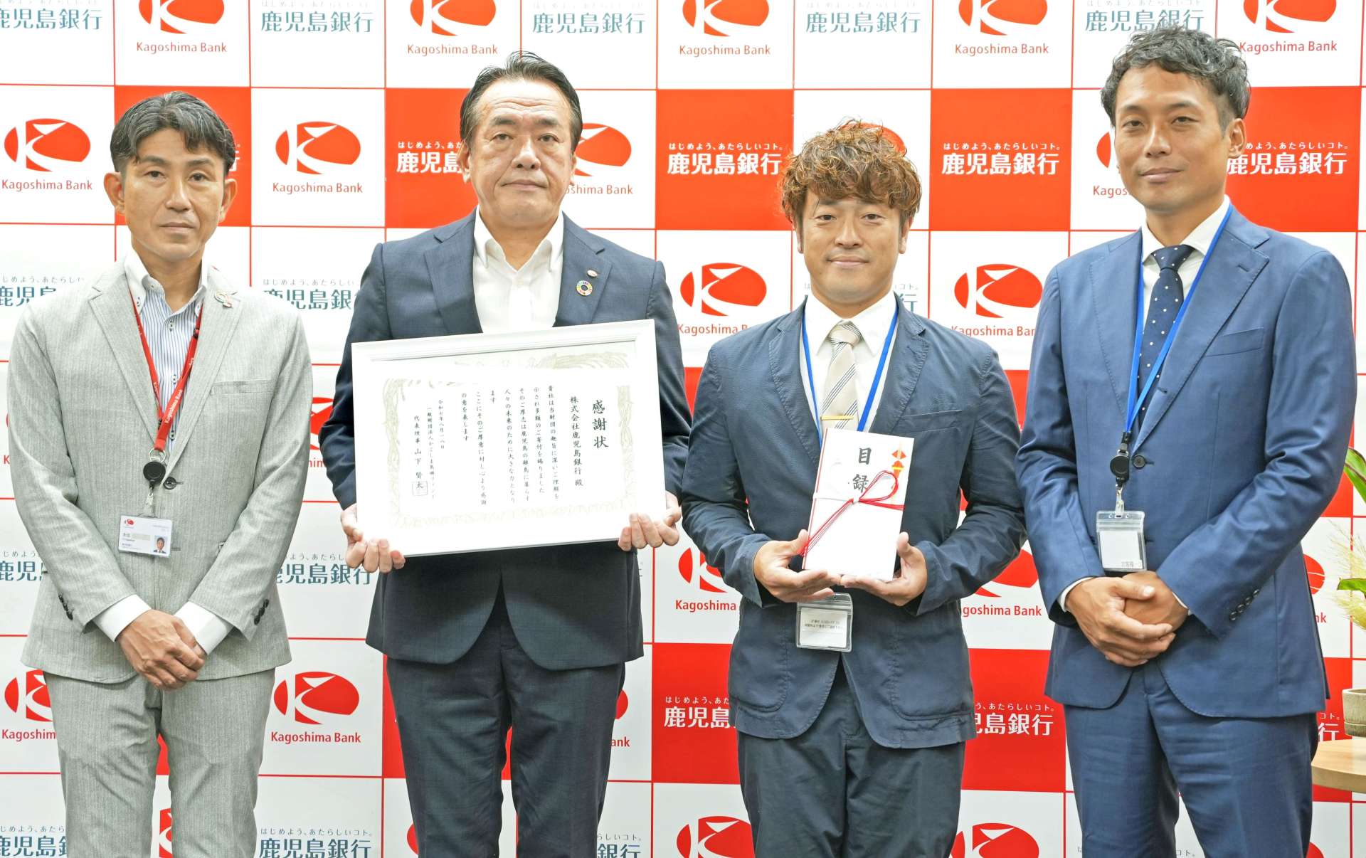 寄付贈呈式の参加者ら＝１８日、鹿児島市金生町の鹿児島銀行本店ビル