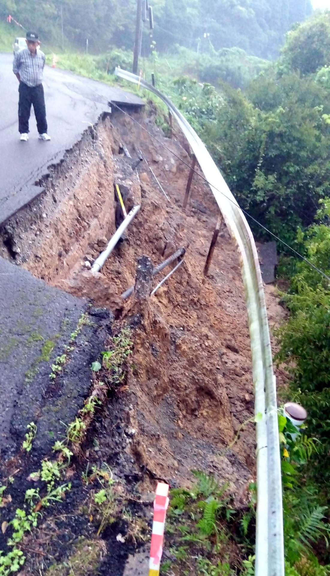 路肩が崩れ、地中の水道管が破損した市道＝２２日午前６時すぎ、日置市日吉町吉利