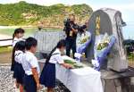 多くの遺体が流れ着いた船越海岸の慰霊碑に献花する小学生＝２４日、宇検村