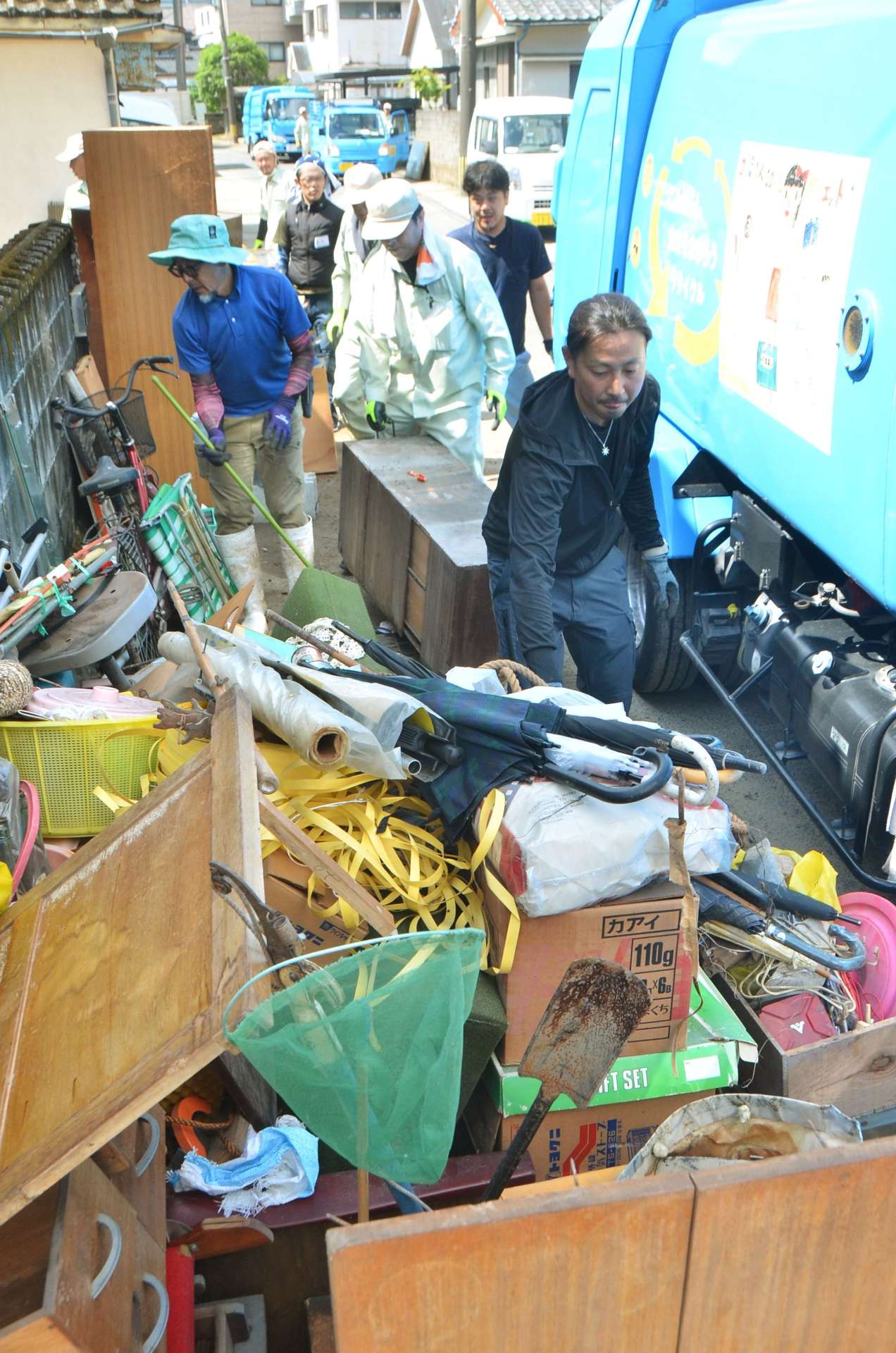 〈関連〉水没した家財道具を屋外に運び出すボランティアや市職員ら＝２４日午前、鹿児島市和田３丁目