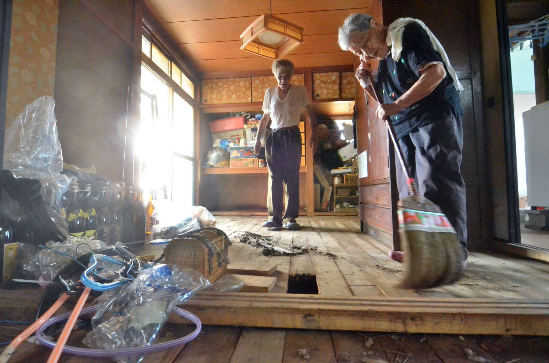 床上まで浸水した自宅を掃除する藤元ミエ子さん（右）＝２４日午前、鹿児島市和田３丁目