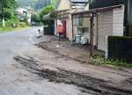 大雨の影響で流れ出た土砂が広がった箇所を測る人々＝鹿児島市本城町
