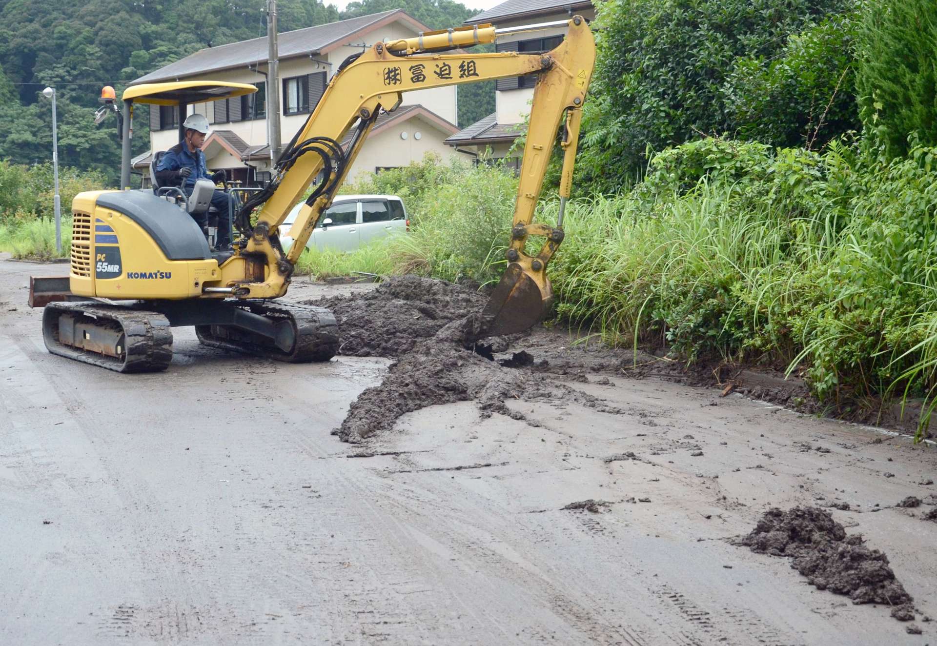 大雨の影響で流れ出た土砂をショベルカーで一カ所に集める人々＝鹿児島市本城町