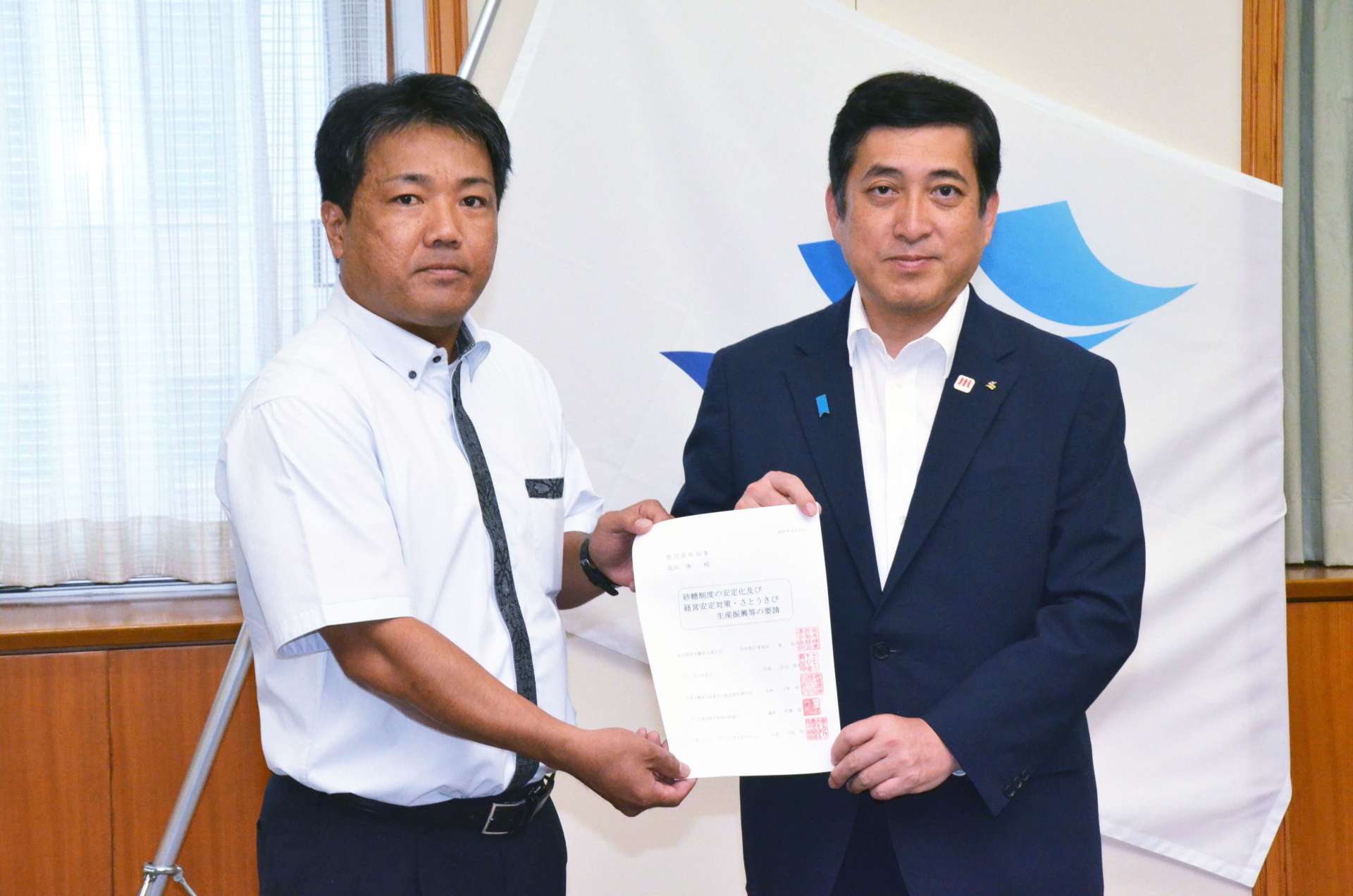 要請書を手渡した奄美糖業労働組合連合会の富祐司中央執行委員長（左）＝２７日、鹿児島県庁