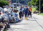 災害ごみが積まれた集落を歩き、活動場所へ向かうボランティア＝２８日、南さつま市加世田内山田（有村美千代撮影）