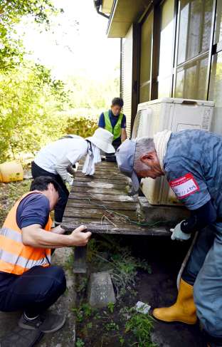 冠水して傾いたテラスを持ち上げるボランティア＝２８日、南さつま市加世田内山田